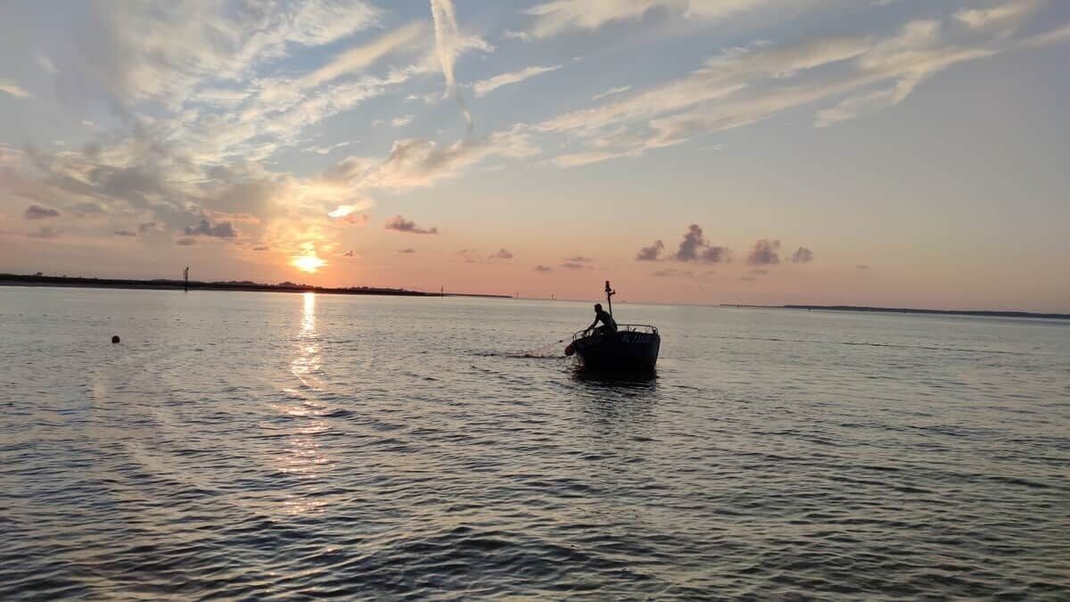 Een boot op kalm water met een zonsondergang op de achtergrond.