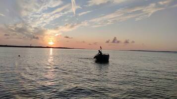 Een boot op kalm water met een zonsondergang op de achtergrond.