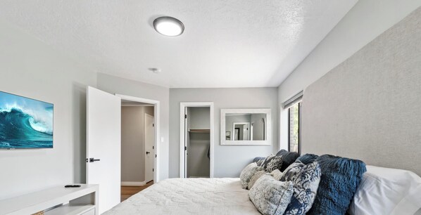 A bedroom with a bed, a TV, a closet, and a mirror. - Casa De Paradise Hills (Albuquerque)