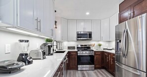 A modern kitchen with white cabinets, stainless steel appliances, and a central island.