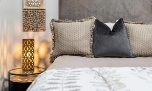 Un lit avec deux oreillers, un mur à texture et un élément décoratif mural.