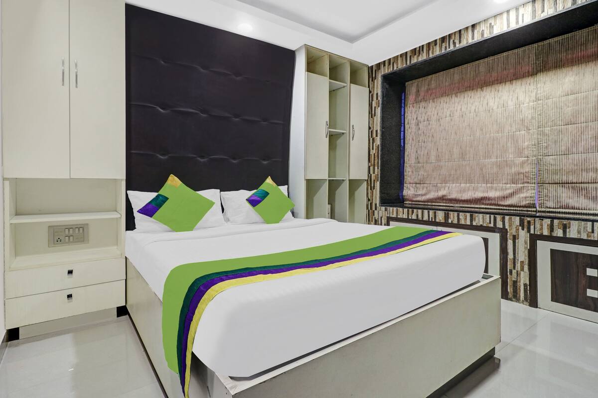 A modern bedroom with a large bed, built-in wardrobe, and a decorative headboard.