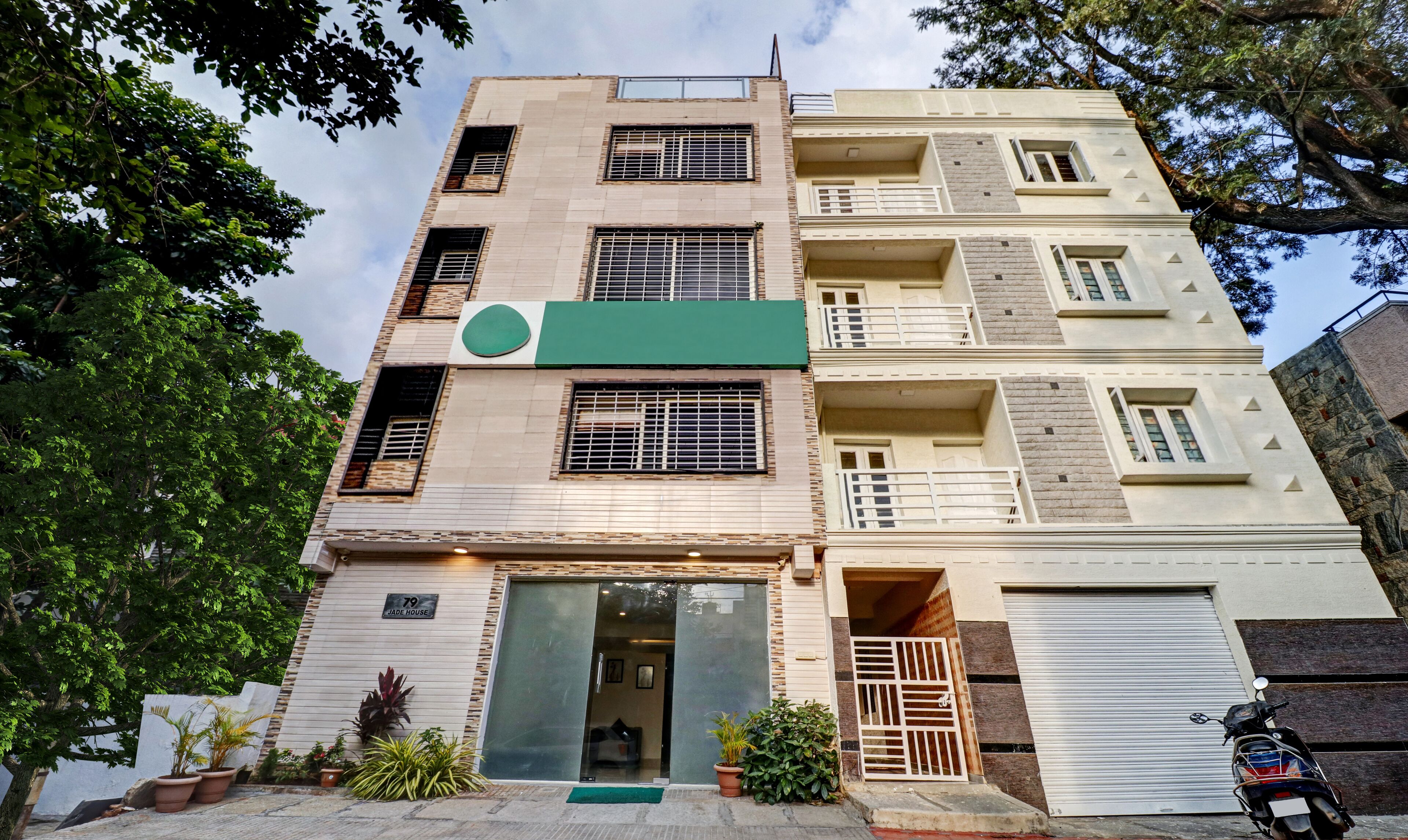 A multi-story building with a green sign, a visible entrance, and a parked motorcycle.