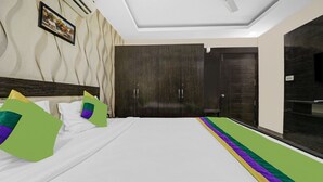 A hotel room with a large bed, a wardrobe, a mirror, and a ceiling fan. - Treebo Elite Premium Homes (Bengaluru)