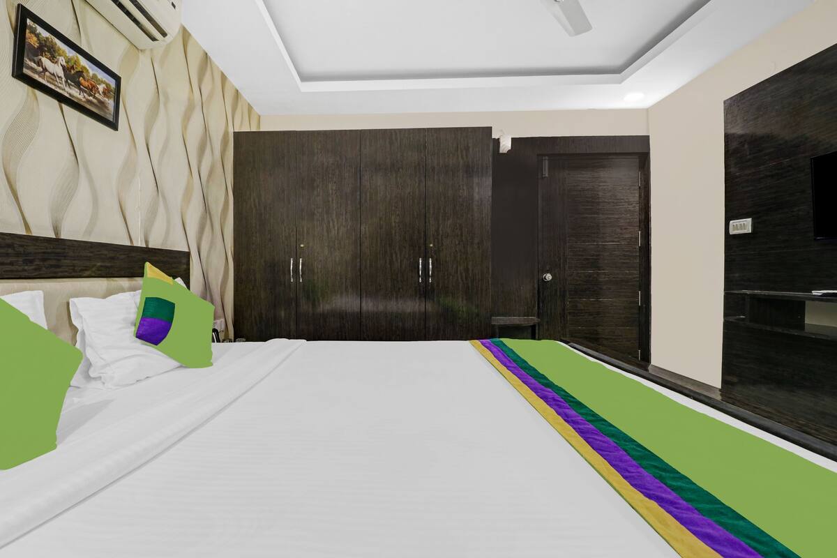 A hotel room with a bed, a wardrobe, a mirror, and a picture on the wall.