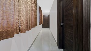 A hallway with patterned curtains, a wooden door, and a tiled floor. - Treebo Elite Premium Homes (Bengaluru)