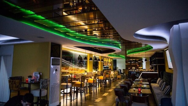 Un restaurant moderne doté d’un bar, de différents espaces pour s’asseoir et d’une cuisine ouverte.