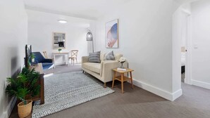 Ein modernes Wohnzimmer mit Sofa, Couchtisch und Essbereich im Hintergrund.
