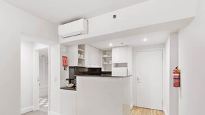 Eine moderne Küche mit weißen Schränken, einem eingebauten Backofen und einem Feuerlöscher.