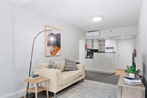 A living room with a sofa, a coffee table, a floor lamp, and a painting on the wall.