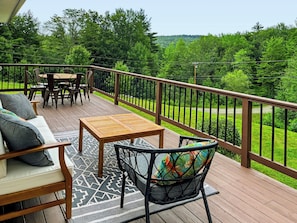 A wooden deck with outdoor furniture, including a sofa, chairs, and a table.