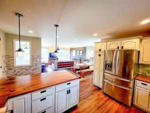 A spacious kitchen with a large island, stainless steel appliances, and a stone accent wall.