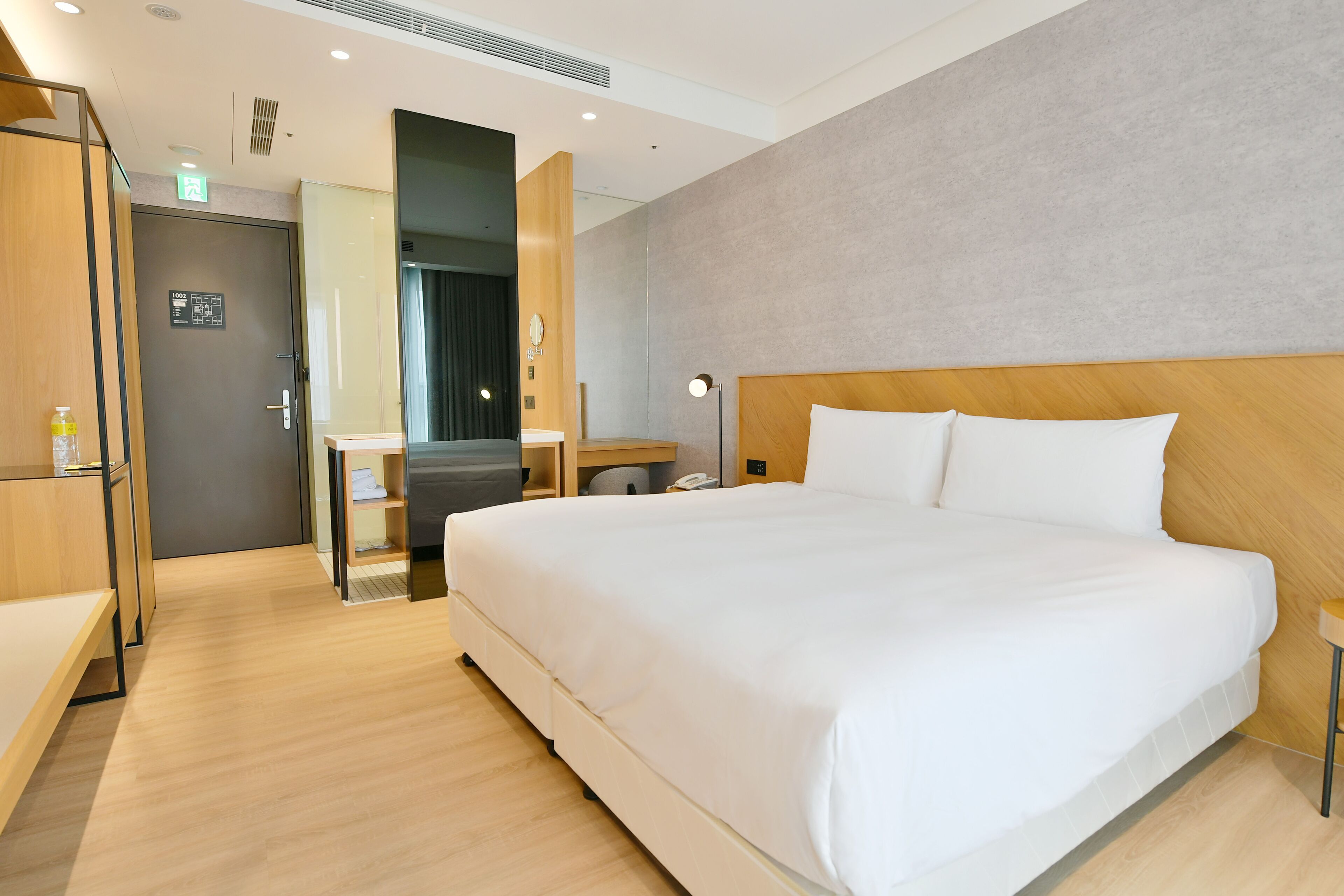 Quarto de hotel com uma cama grande, uma escrivaninha, uma cadeira e um guarda-roupa.