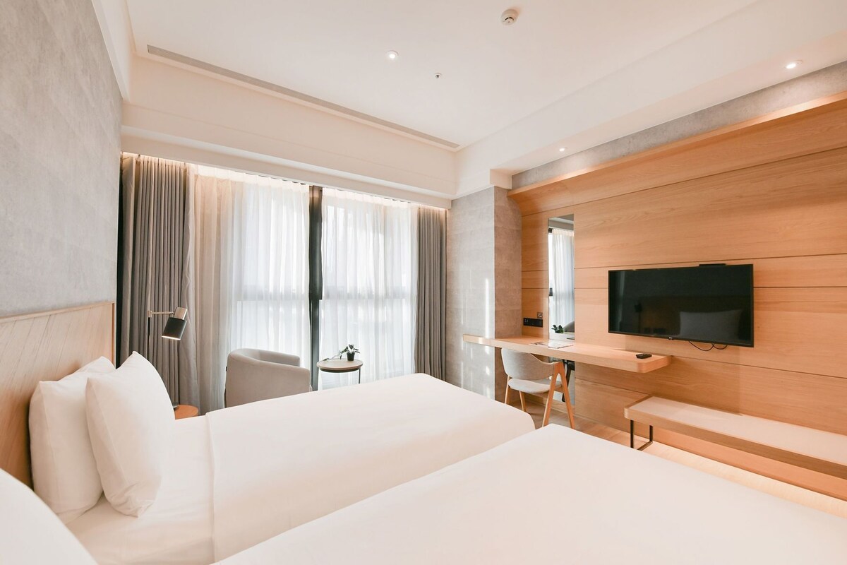 Une chambre d’hôtel avec un lit, un bureau, une télévision et une chaise.