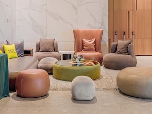 A modern lounge area with a sofa, ottomans, a round coffee table, and a small side table. - CHECK inn Select New Taipei Sanchong (New Taipei City)