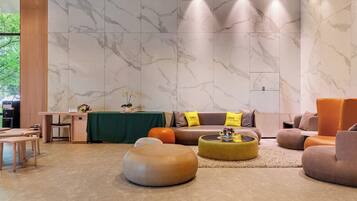 Een moderne lobby met een receptiebalie, een zithoek en een groot raam.