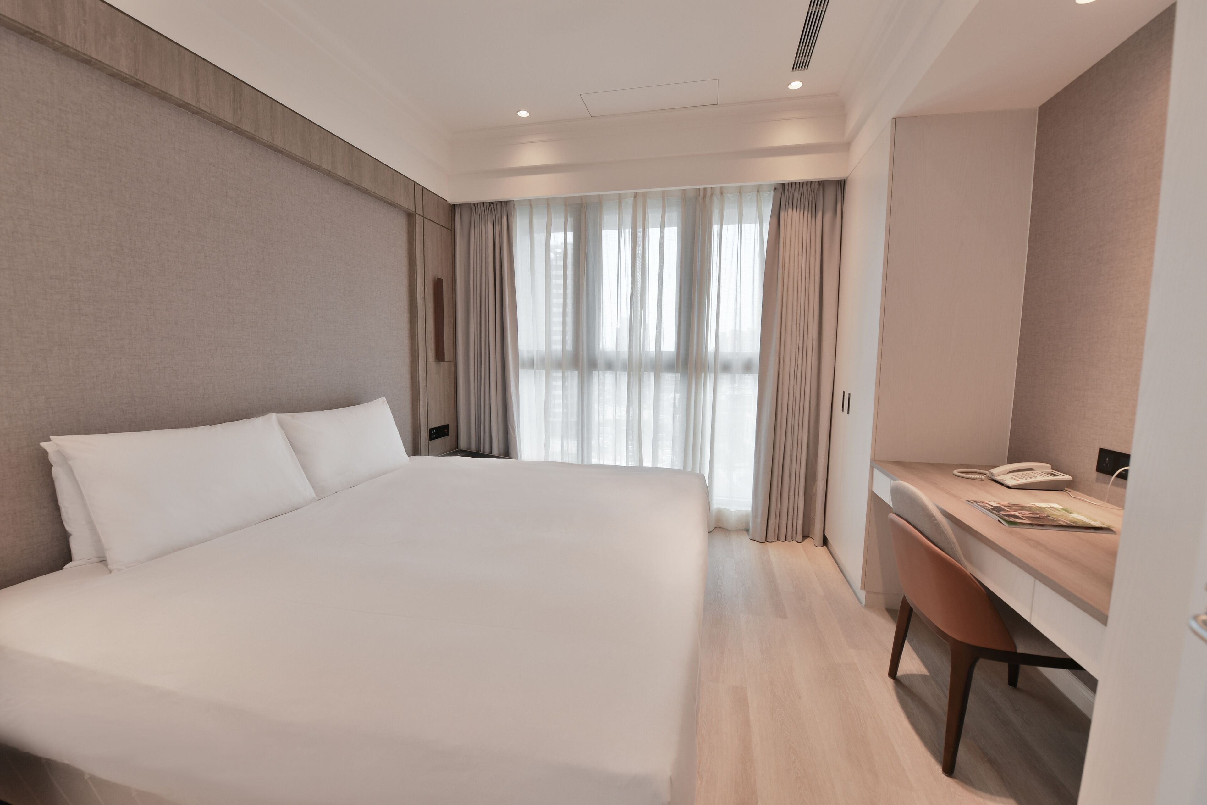 Quarto de hotel moderno com uma cama grande, uma escrivaninha e uma cadeira.