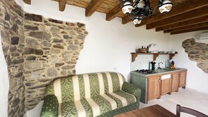 A rustic kitchen with stone walls, a wooden ceiling, and a green patterned sofa. - Premium Townhouse: Panoramic Rooftop Terrace with Nature and Ocean Views (Posada)