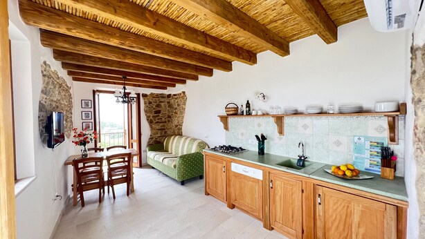 A rustic kitchen with wooden beams, a stone wall, and a dining area with a table and chairs. - Premium Townhouse: Panoramic Rooftop Terrace with Nature and Ocean Views (Posada)