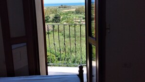 A bedroom with a bed, an open door leading to a balcony with a view of the sea and greenery. - Premium Townhouse: Panoramic Rooftop Terrace with Nature and Ocean Views (Posada)