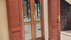 A wooden door with glass panels and a metal gate, set in a building with a beige exterior and a visible staircase. - Premium Townhouse: Panoramic Rooftop Terrace with Nature and Ocean Views (Posada)
