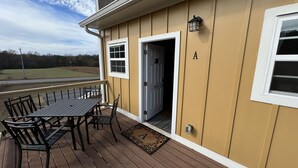 A wooden deck with a table and chairs, a door, and a window with the letter 'A' on the wall. - 2 BR,1BA Spacious Mountain View Suite near Cherokee National Forest, Ocoee River (Benton)
