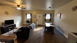A living room with a TV, sofa, and coffee table. There is a dining area with a table and chairs. - 2 BR,1BA Spacious Mountain View Suite near Cherokee National Forest, Ocoee River (Benton)
