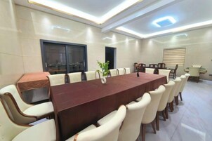 Un salón de conferencias con una larga mesa, sillas y una planta pequeña.