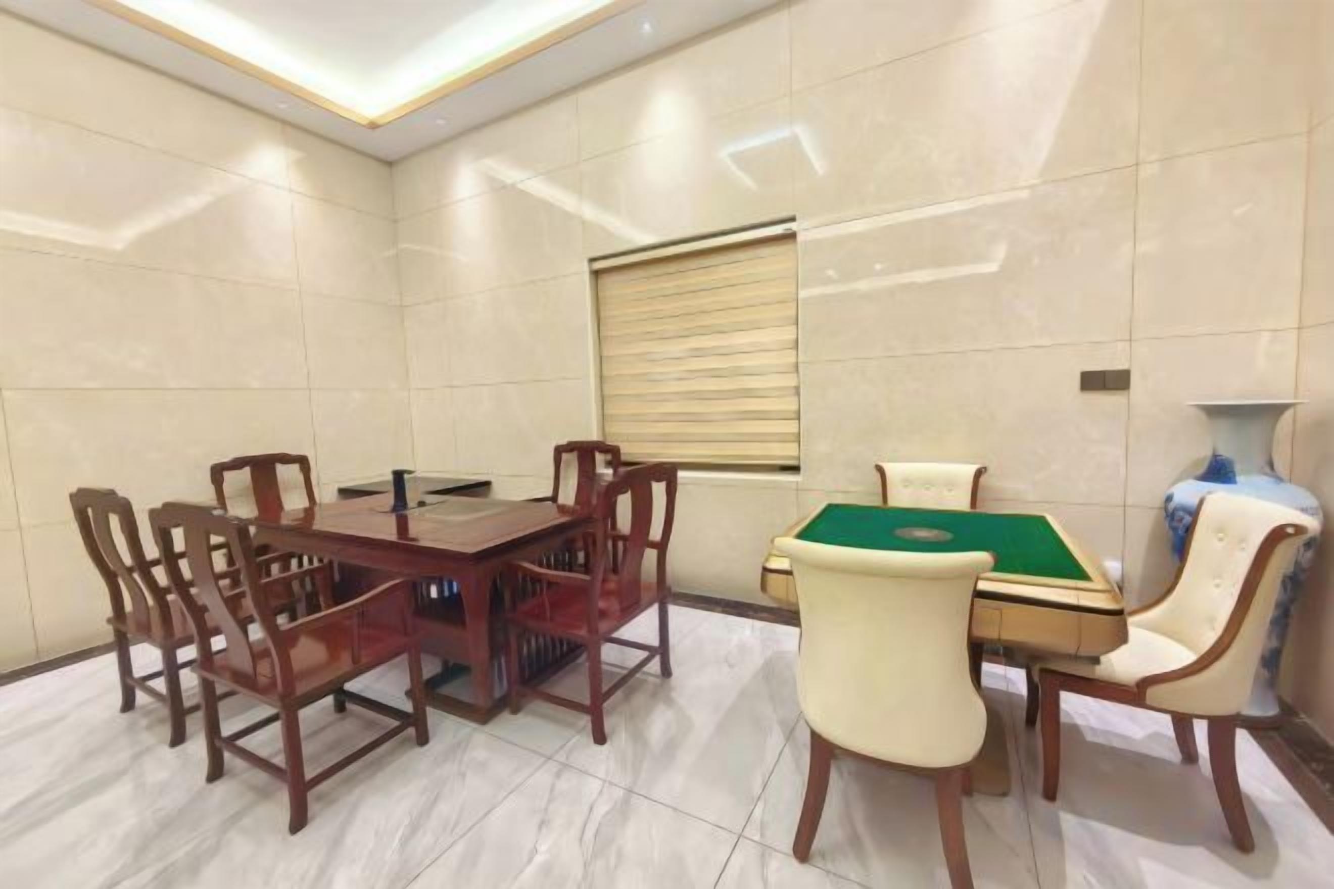A room with a rectangular dining table, six chairs, a pool table, and a lamp.