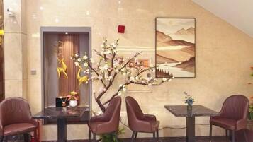 A lobby with a reception desk, seating area, and a decorative tree.
