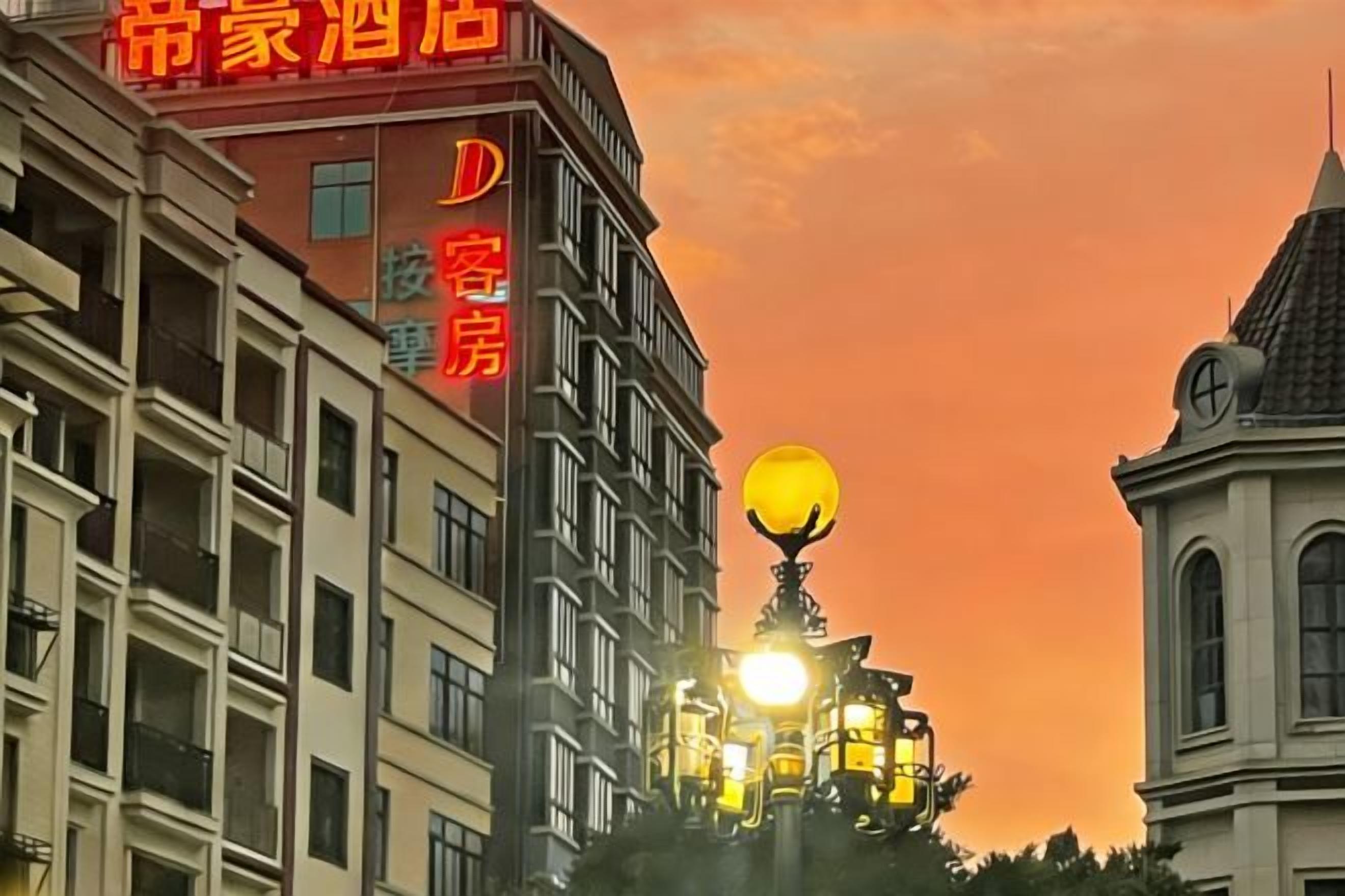 Un edificio de hotel con un cartel llamativo en caracteres chinos, una gran lámpara esférica iluminada y un estilo arquitectónico tradicional con techo a dos aguas.