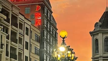 Un edificio de hotel con un cartel llamativo en caracteres chinos, una gran lámpara esférica iluminada y un estilo arquitectónico tradicional con techo a dos aguas.