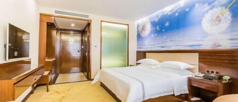 Habitación de hotel con cama, escritorio, silla, televisor y un cuadro de un paisaje marino.