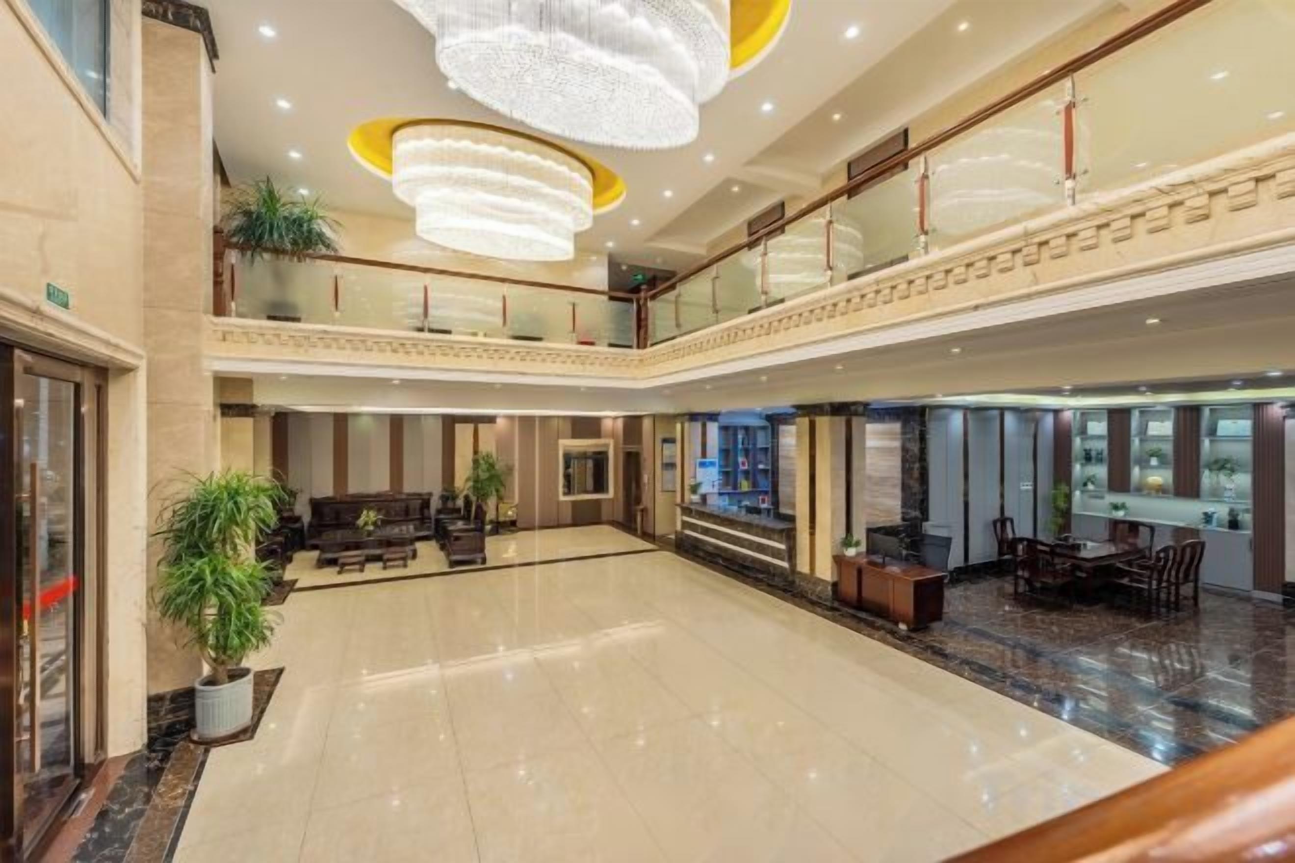 A spacious lobby with a chandelier, seating area, and a reception desk.