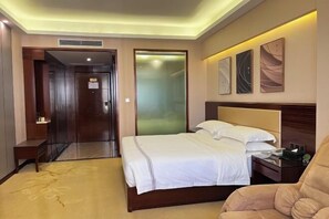 Una habitación de hotel con una cama, una silla, una mesita de noche y una pared decorada con obras de arte.