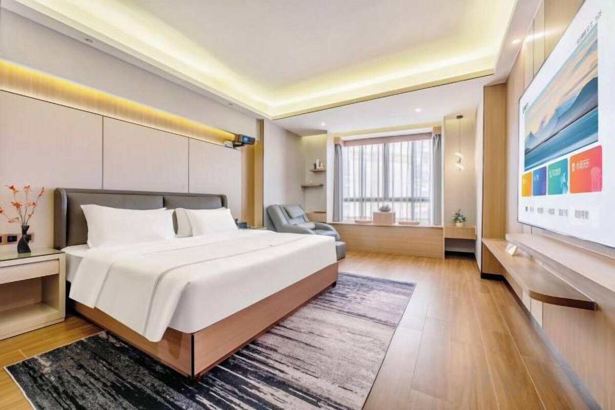 Una habitación de hotel moderna con una cama grande, un escritorio y una zona de estar.