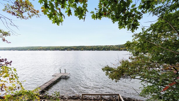 Une jetée en bois s’étendant sur un lac paisible, entourée d’arbres et bordée d’une rive rocheuse.