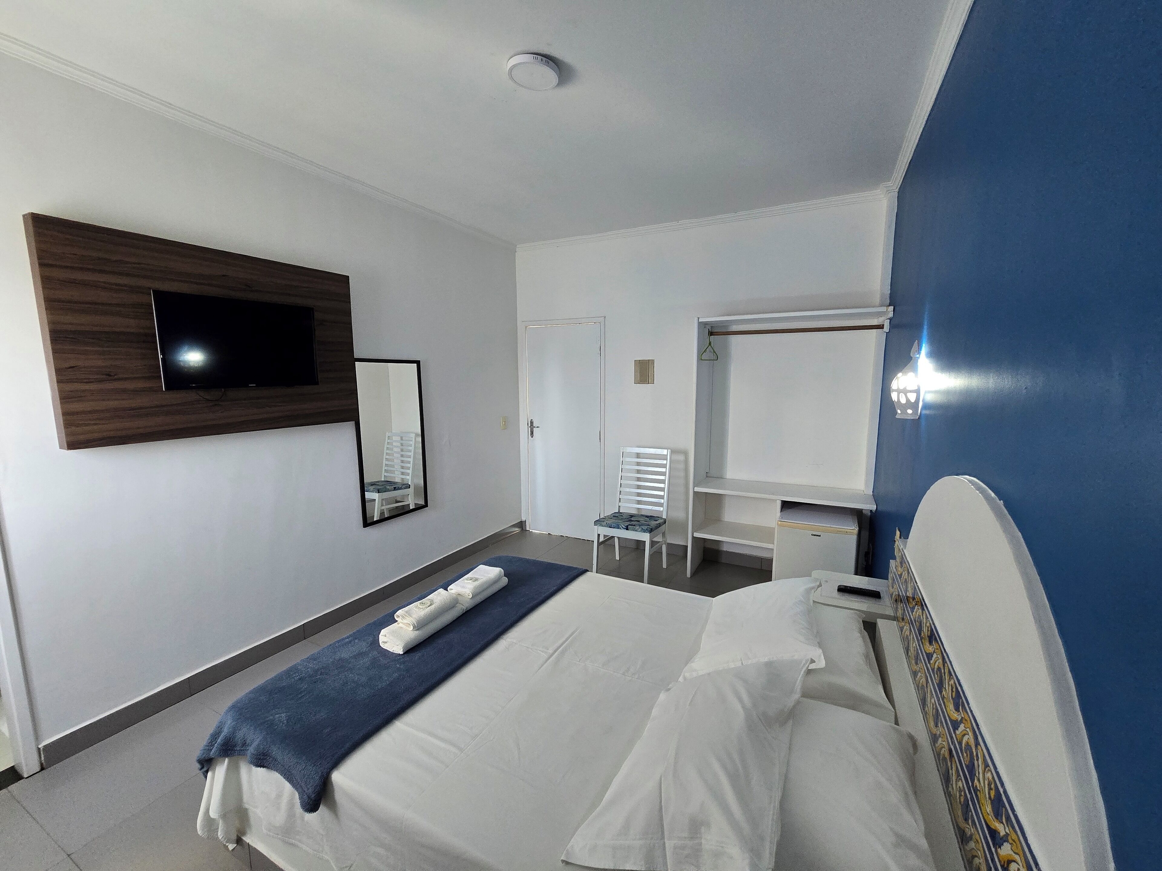 Een hotelkamer met een bed, een bureau, een stoel, een televisie en een spiegel.