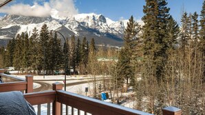 A mountain view with snow-covered peaks, a winding road, and a mix of evergreen and deciduous trees. - L202 Canmore Vista- Free Parking, Hot tub, Pool, View, BBQ, 2BR, 2BT, Sleeps 6 (Canmore)