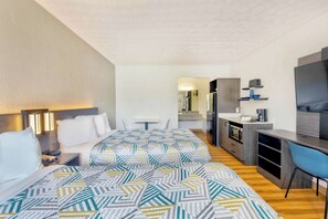 Une chambre d’hôtel avec deux lits, un bureau, une chaise, une télévision et une kitchenette.