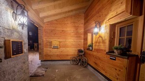 A wooden interior with a stone wall, a wooden cabinet with a keypad, a sign, and a small window with plants. - Engadin Chalet Appartment- Val Bever St.Moritz ideal for 2 persons. New! (Bever)