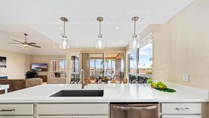 Uma cozinha moderna com uma ilha grande, eletrodomésticos de aço inoxidável e iluminação pendente.