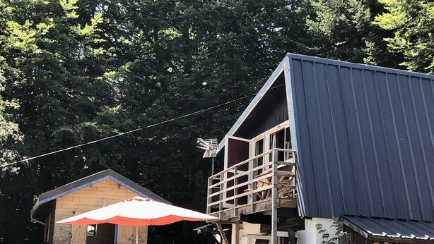 Un chalet rustique doté d’une terrasse en bois, d’un balcon et d’un espace extérieur aménagé et abrité.