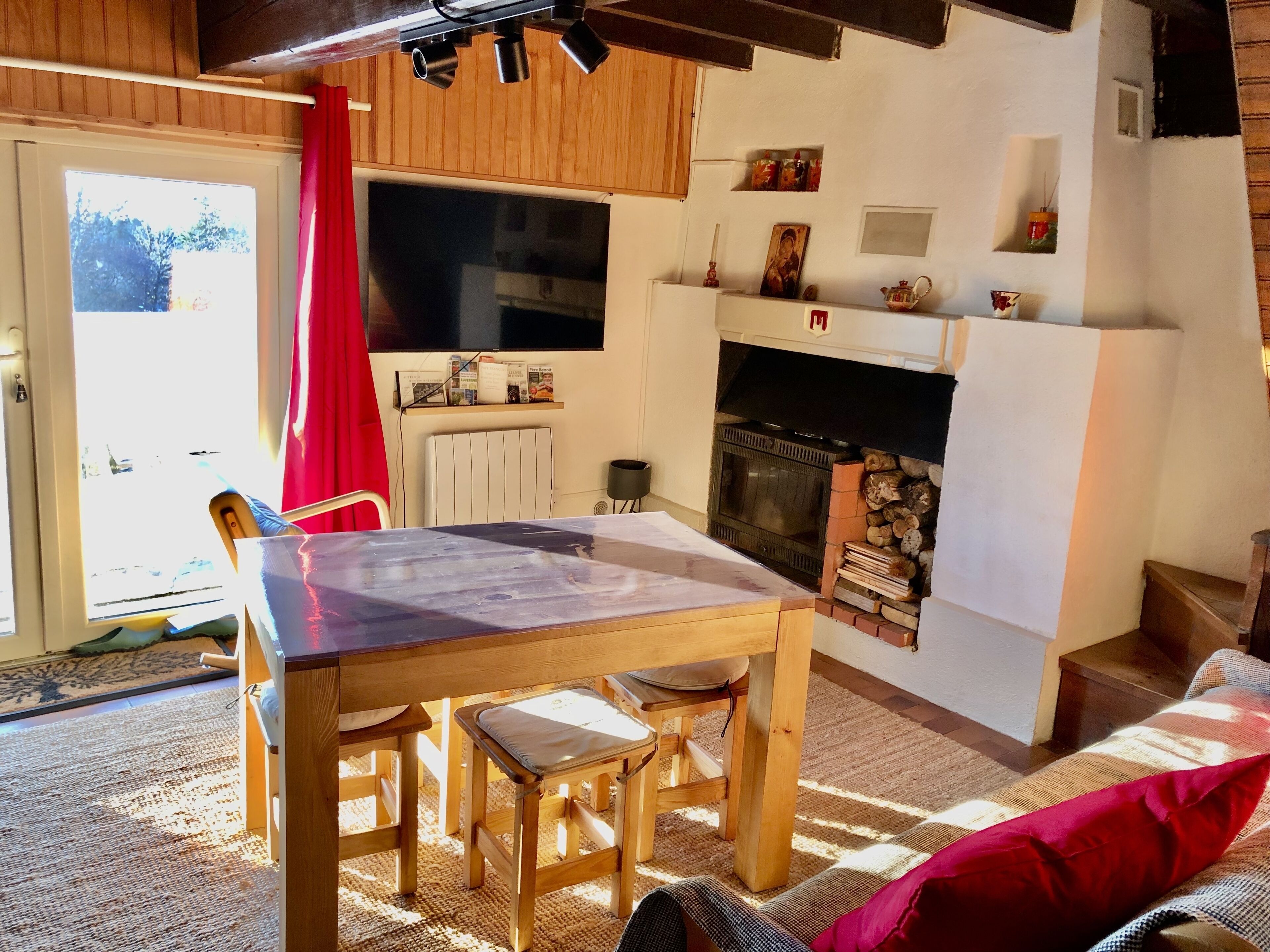 Una sala de estar acogedora con una mesa de madera, sillas, chimenea y vistas al exterior.