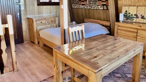 Une pièce en bois avec un lit, une table et un banc.