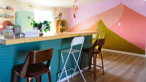 Una cucina con un piano di lavoro verde acqua, un frigorifero e sgabelli da bar.