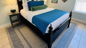 A bedroom with a bed, a nightstand, a lamp, a ceiling fan, a heart-shaped wall decoration, and a window with blinds. -  Bayside Cottage 4 miles to Destin, Shopping & Beaches, minutes to Elgin AFB (Niceville)