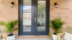A double door with glass panels, flanked by two potted plants, and a bench with a cushion. -  Bayside Cottage 4 miles to Destin, Shopping & Beaches, minutes to Elgin AFB (Niceville)
