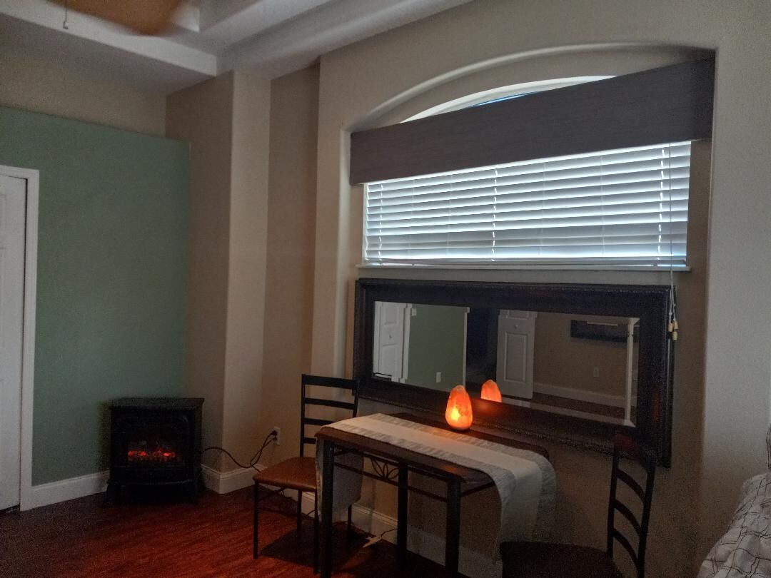 A room with a fireplace, a table with chairs, a window with blinds, and a door.