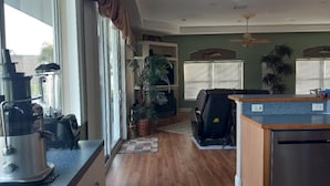 A kitchen with a coffee maker, a blender, and a refrigerator. There are potted plants and a window with blinds. - Luxury Bayview Wellness Retreat w/Pool, Salt-Water Jacuzzi, Hot Tub...+ more! (Bradenton)